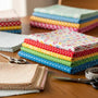 Colorful quilting fabrics arranged on a table with scissors and measuring tape, representing online fabric purchasing