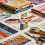Colorful quilting fabrics and tools illustrating the fussy cutting technique for unique quilt designs